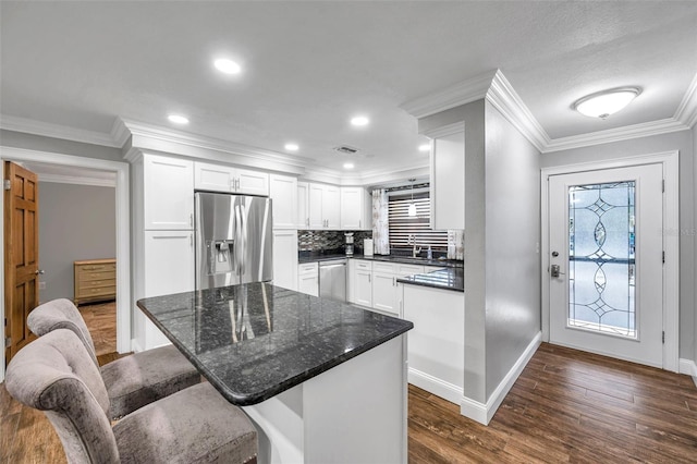 kitchen with a breakfast bar, appliances with stainless steel finishes, decorative backsplash, and white cabinetry