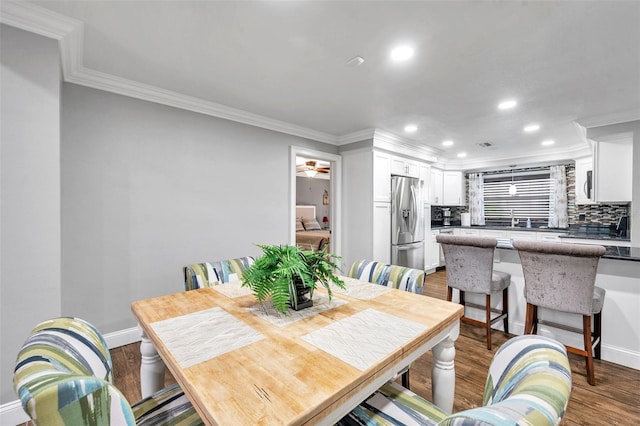 dining area with hardwood / wood-style floors, crown molding, and sink