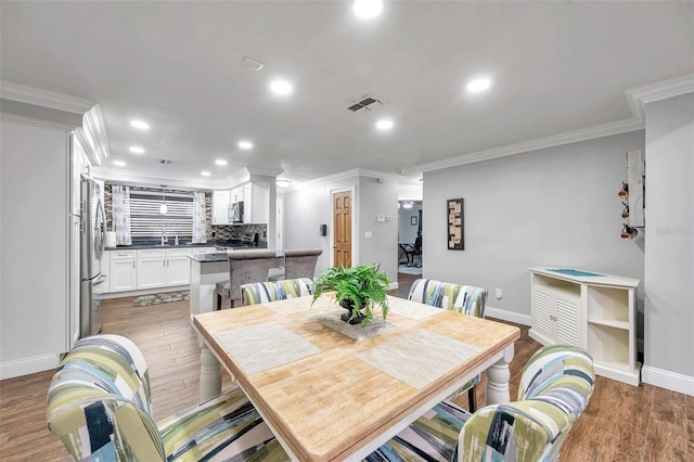 dining space with dark hardwood / wood-style floors, sink, and crown molding