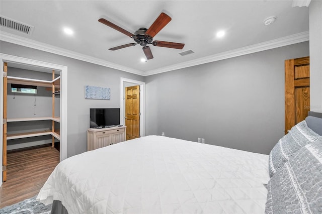 bedroom featuring hardwood / wood-style floors, ceiling fan, a spacious closet, and crown molding