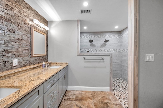 bathroom with a tile shower and vanity