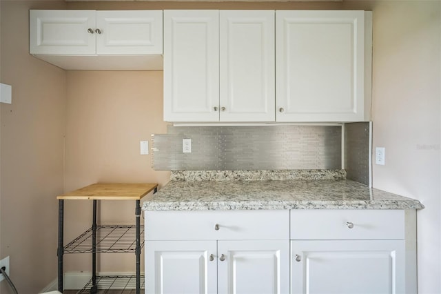 kitchen featuring light stone counters, white cabinetry, and tasteful backsplash