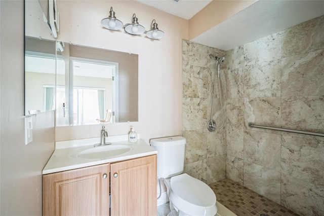 bathroom featuring vanity, toilet, and a tile shower