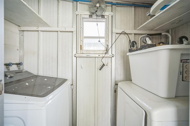 clothes washing area featuring wood walls and independent washer and dryer