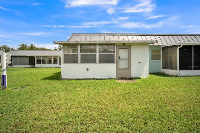 back of property with a lawn and a sunroom