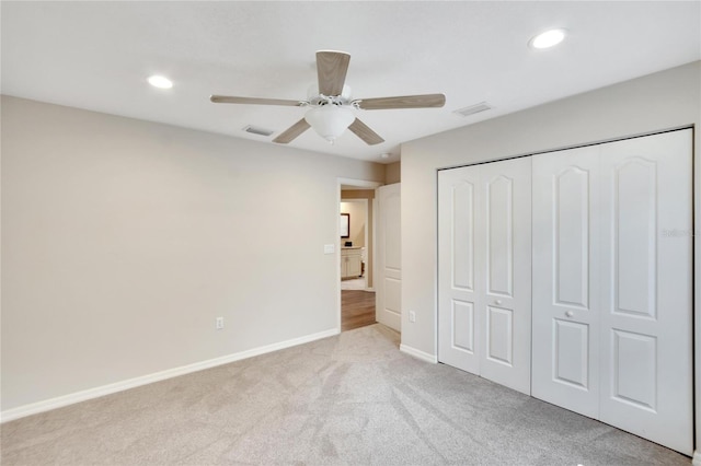 unfurnished bedroom with ceiling fan, light colored carpet, and a closet