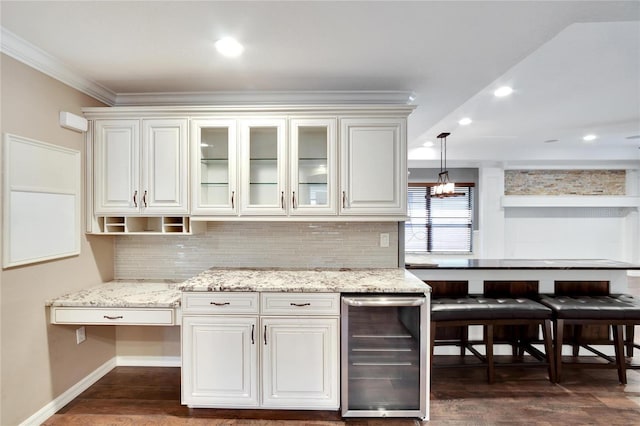 kitchen with tasteful backsplash, white cabinets, beverage cooler, hanging light fixtures, and ornamental molding