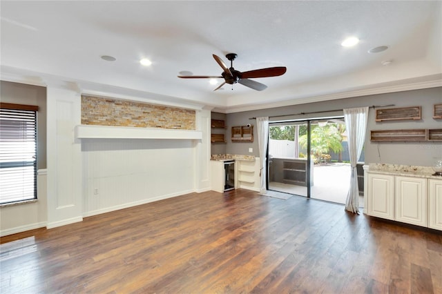 unfurnished living room featuring crown molding, dark wood-type flooring, and ceiling fan