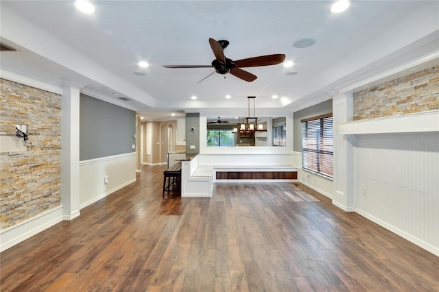 unfurnished living room with ceiling fan with notable chandelier and dark hardwood / wood-style flooring