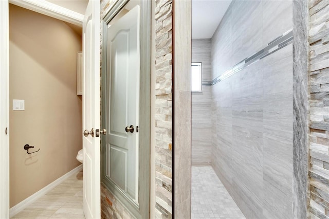 bathroom featuring tiled shower and toilet