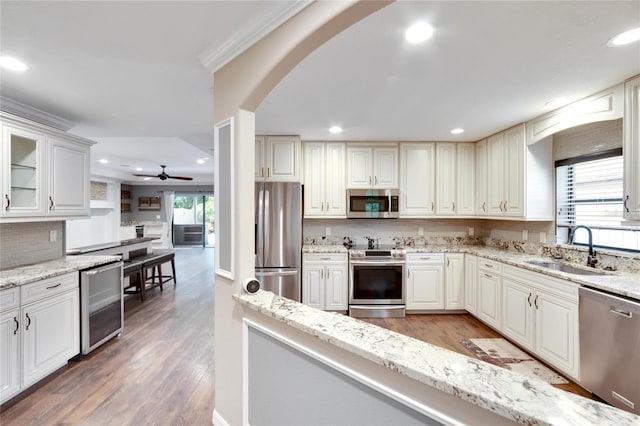 kitchen featuring wine cooler, sink, light stone counters, appliances with stainless steel finishes, and dark hardwood / wood-style floors