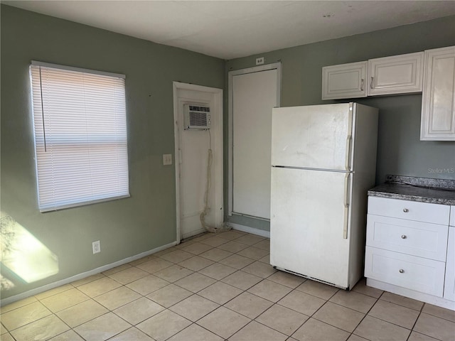 kitchen with light tile patterned floors, white cabinetry, white fridge, and a wall mounted AC