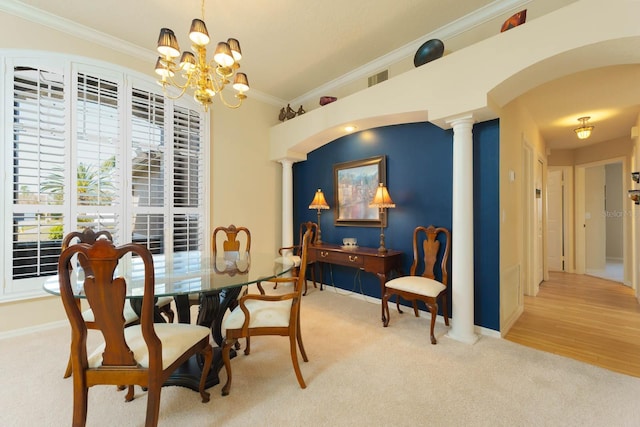 dining area featuring ornate columns, a chandelier, carpet, and crown molding