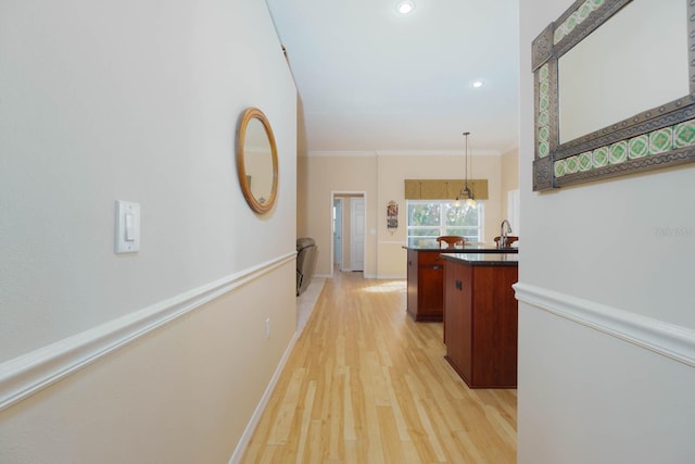 corridor with an inviting chandelier, ornamental molding, light hardwood / wood-style flooring, and sink