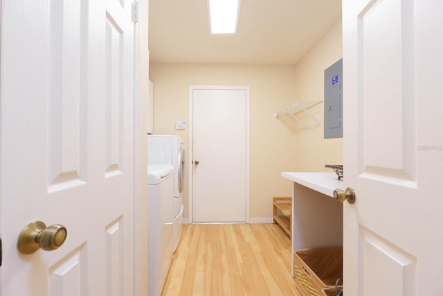 laundry area with electric panel, washer and dryer, and wood-type flooring