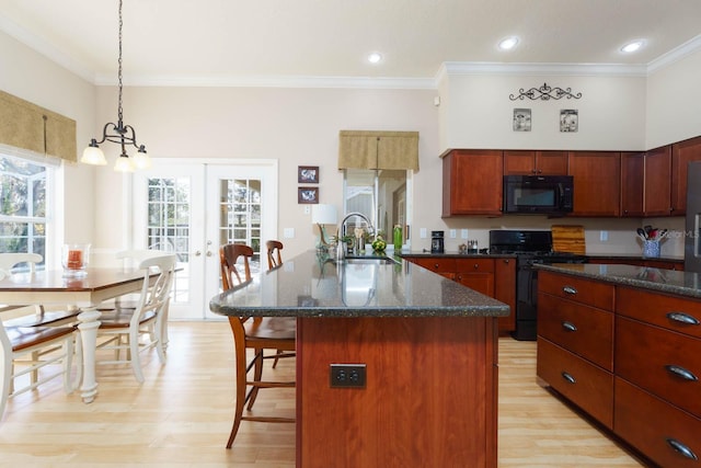 kitchen with black appliances, hanging light fixtures, an island with sink, ornamental molding, and sink