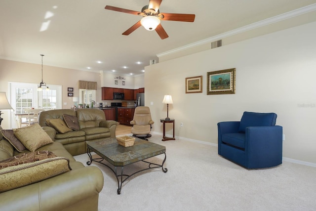 carpeted living room with ceiling fan and crown molding