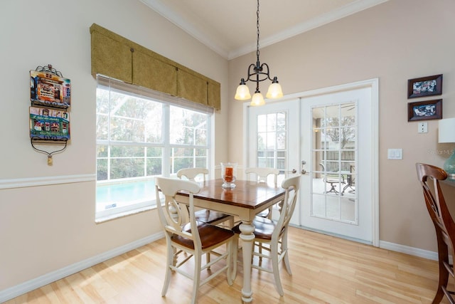 dining space featuring a notable chandelier, light wood-type flooring, ornamental molding, and plenty of natural light