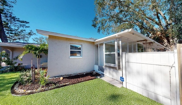 view of home's exterior featuring a lawn and a sunroom