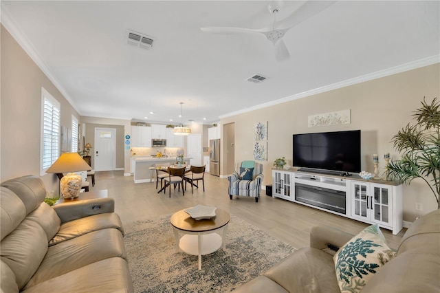 living room with ceiling fan, crown molding, and light hardwood / wood-style flooring