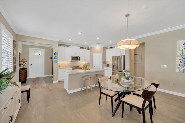 dining area with sink, ornamental molding, and light wood-type flooring