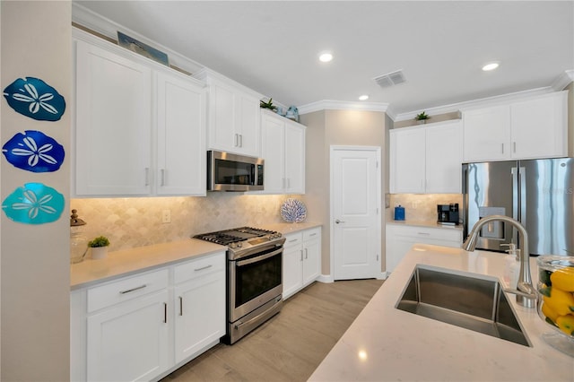 kitchen with appliances with stainless steel finishes, white cabinetry, and sink