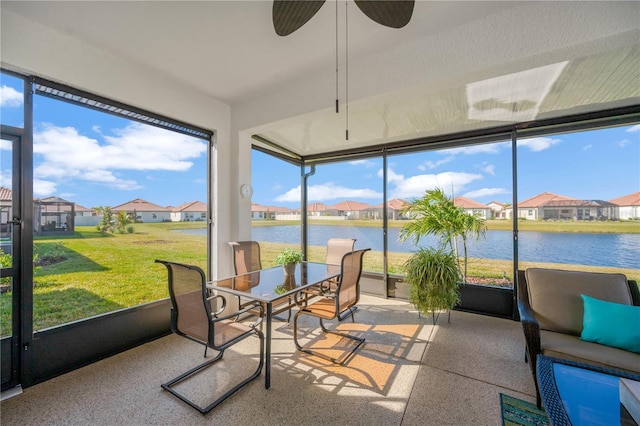 sunroom featuring ceiling fan and a water view