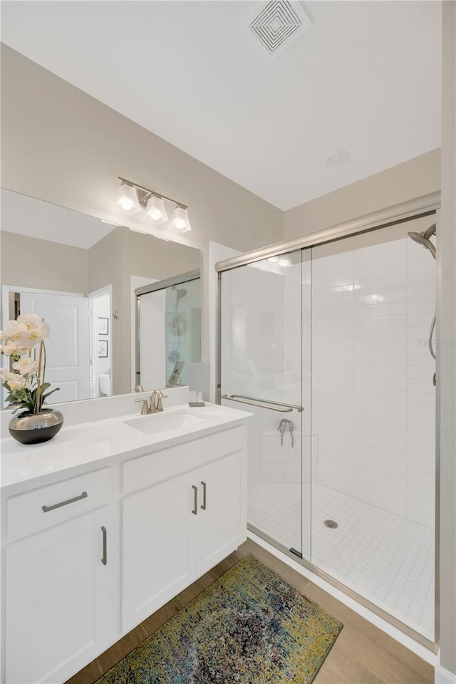 bathroom with a shower with shower door, vanity, and wood-type flooring