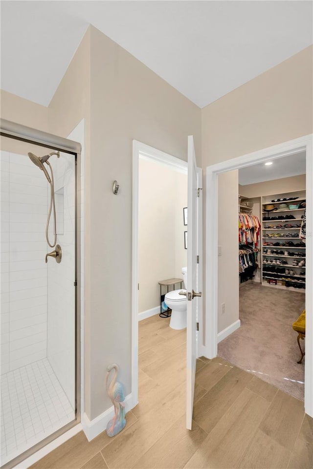 bathroom with toilet, wood-type flooring, and a shower with door