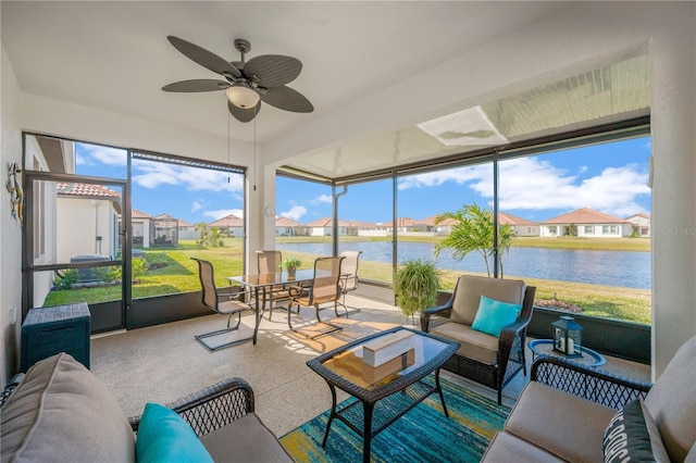 sunroom with ceiling fan and a water view