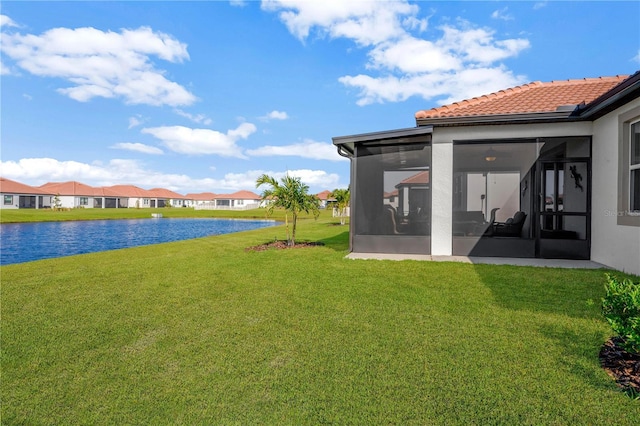 view of yard with a sunroom and a water view