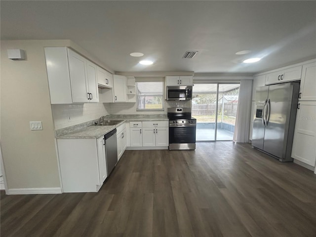 kitchen with dark hardwood / wood-style floors, decorative backsplash, white cabinets, appliances with stainless steel finishes, and sink