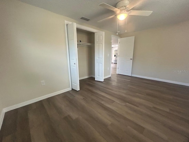 unfurnished bedroom with a textured ceiling, ceiling fan, a closet, and dark hardwood / wood-style floors