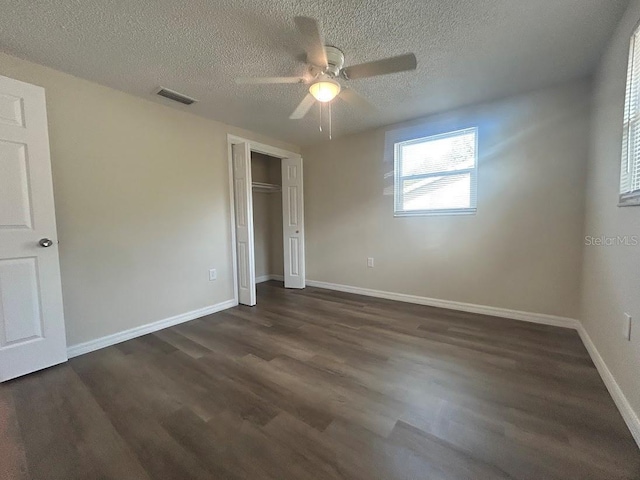 unfurnished bedroom featuring ceiling fan, a closet, a textured ceiling, and dark hardwood / wood-style floors