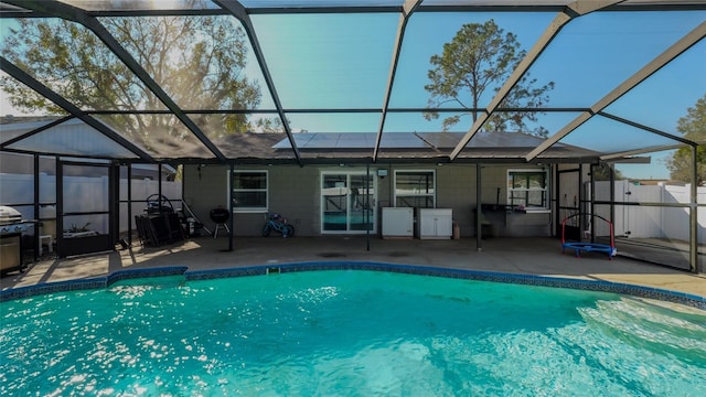 view of pool featuring glass enclosure and a patio area