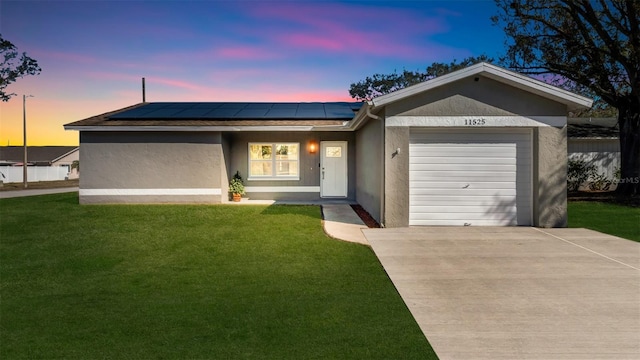 ranch-style house featuring solar panels, a lawn, and a garage