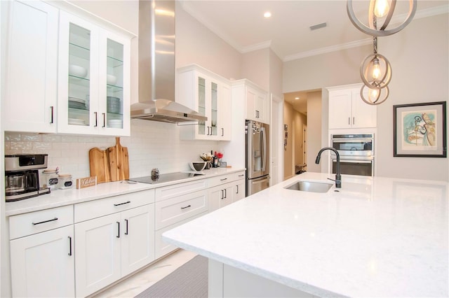 kitchen featuring white cabinetry, appliances with stainless steel finishes, decorative light fixtures, wall chimney exhaust hood, and sink