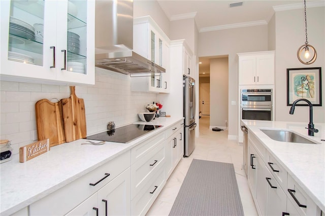 kitchen featuring white cabinetry, stainless steel appliances, decorative light fixtures, wall chimney range hood, and sink