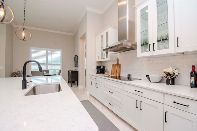 kitchen with decorative light fixtures, black electric stovetop, sink, white cabinets, and wall chimney exhaust hood