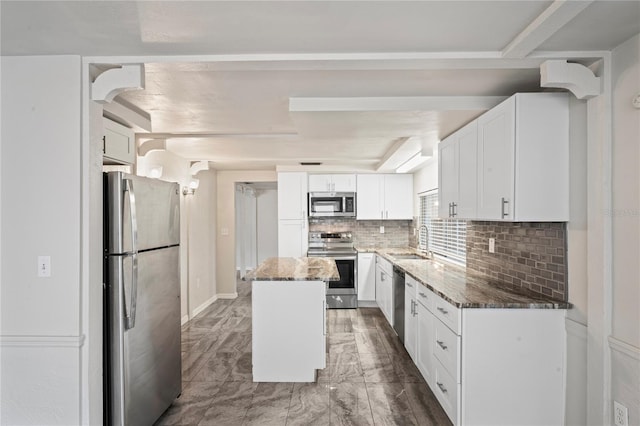 kitchen with appliances with stainless steel finishes, sink, white cabinets, dark stone counters, and a center island