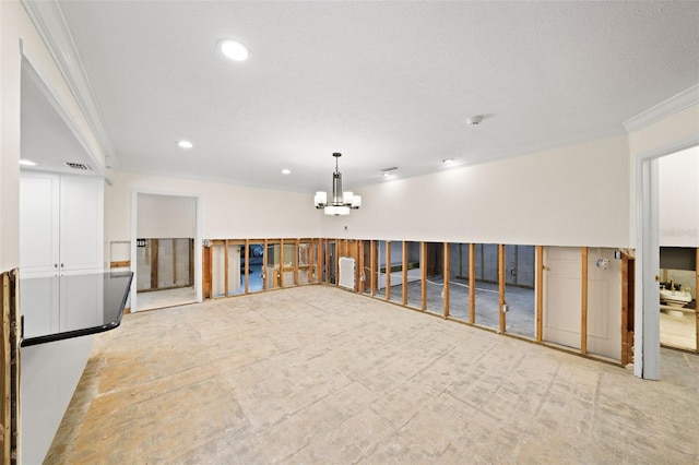 spare room featuring a chandelier, ornamental molding, and a textured ceiling