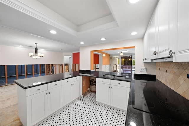 kitchen with kitchen peninsula, white cabinetry, a tray ceiling, and sink