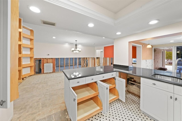 kitchen featuring kitchen peninsula, a notable chandelier, ornamental molding, white cabinets, and decorative light fixtures