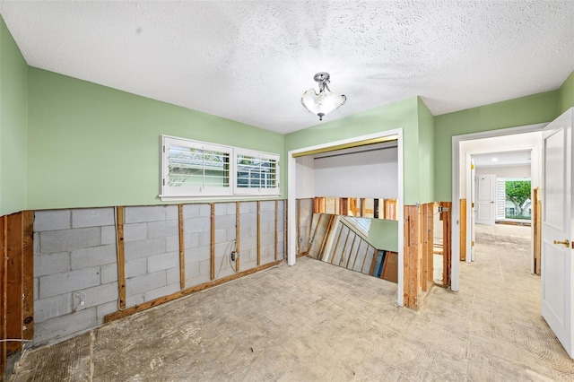 unfurnished bedroom featuring a textured ceiling, a closet, and multiple windows