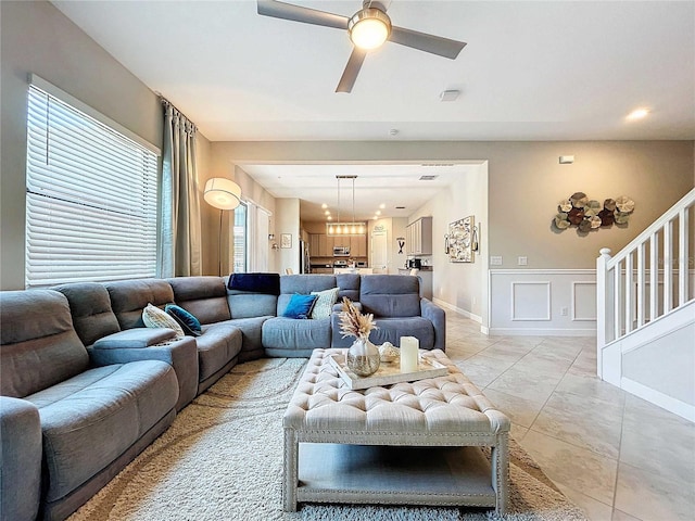 tiled living room with ceiling fan with notable chandelier