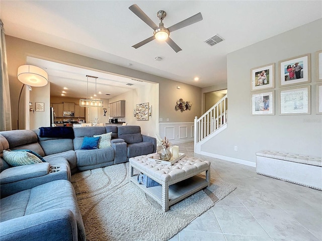 tiled living room featuring ceiling fan with notable chandelier