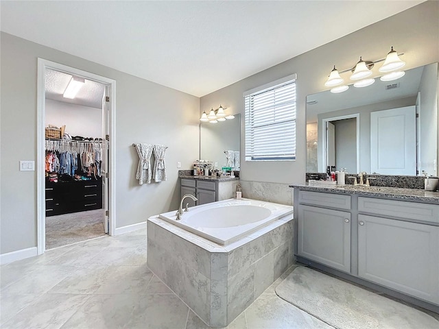 bathroom with tile patterned flooring, vanity, and tiled tub