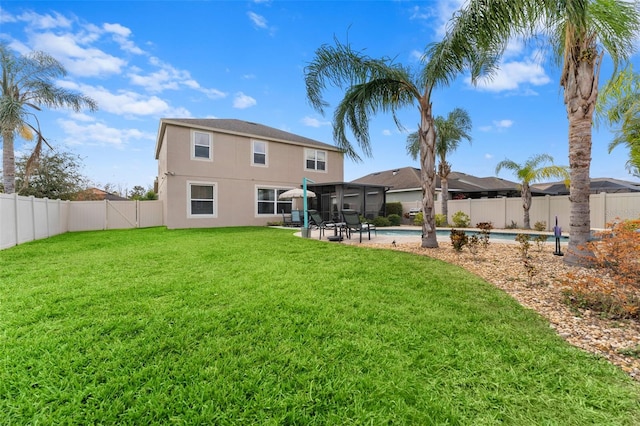 rear view of house featuring a patio, a fenced in pool, and a lawn