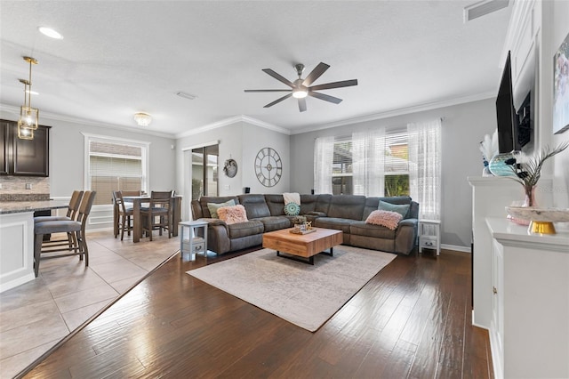 living room with hardwood / wood-style floors, ceiling fan, ornamental molding, a fireplace, and a textured ceiling