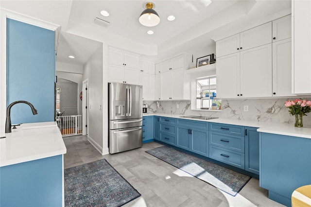 kitchen featuring black electric stovetop, white cabinetry, stainless steel refrigerator with ice dispenser, blue cabinets, and a tray ceiling